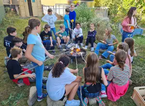 Schülerinnen und Schüler um ein Grillfeuer beim Gartenfest
